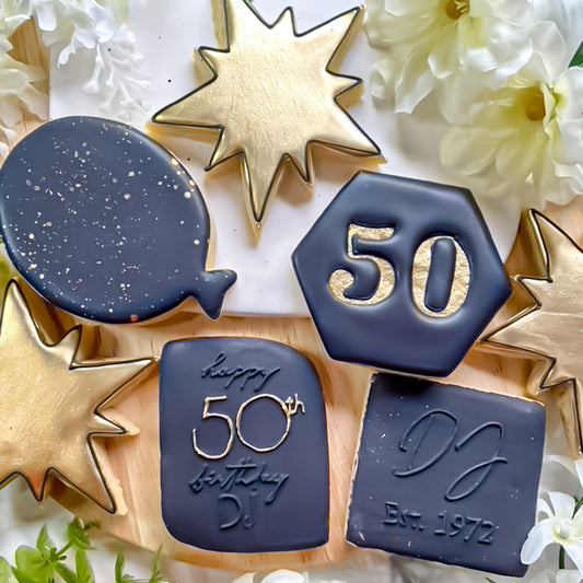 black and gold sugar cookies decorated with the number 50 and geometric shapes