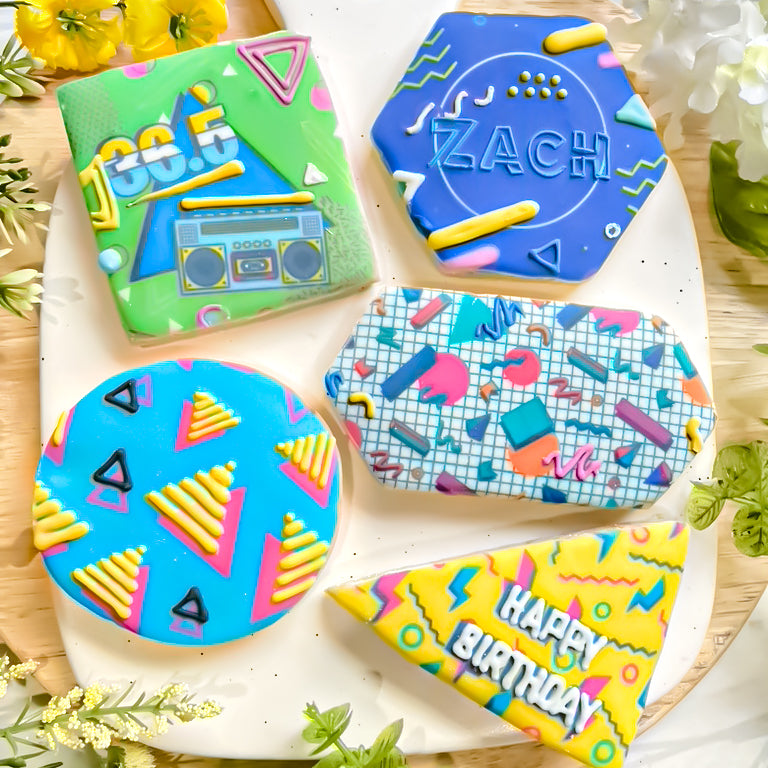 Four rectangular sugar cookies decorated with bright 90's themed patterns and personalized with the name Zach and "Happy Birthday".
