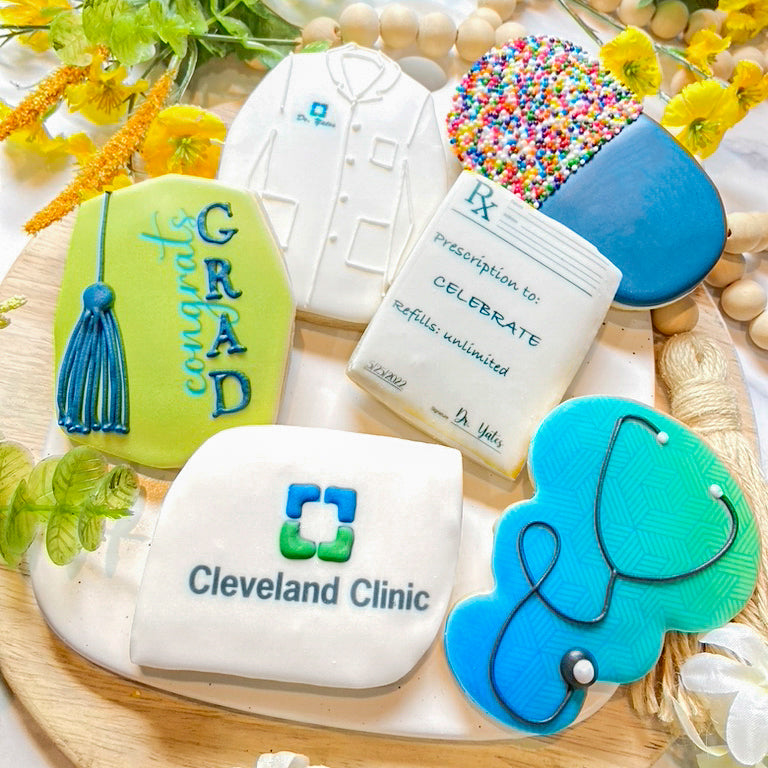 Custom medical-themed graduation cookies, including designs of a stethoscope, lab coat, prescription pad, and Cleveland Clinic logo for celebrating healthcare professionals
