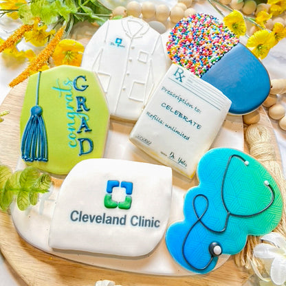 Custom medical-themed graduation cookies, including designs of a stethoscope, lab coat, prescription pad, and Cleveland Clinic logo for celebrating healthcare professionals
